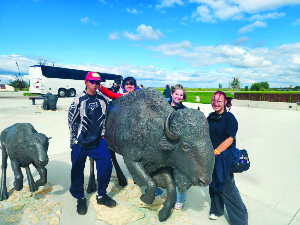 four young people and a statue of a buffalo