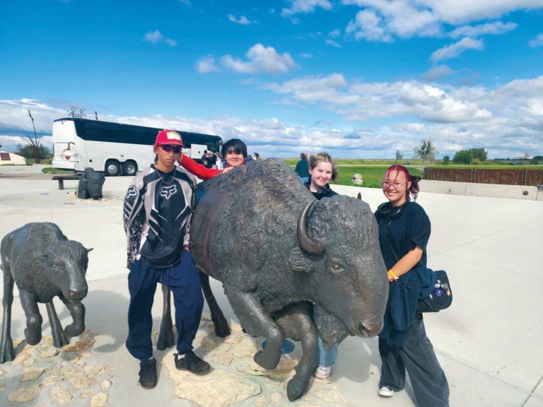 four young people and a statue of a buffalo