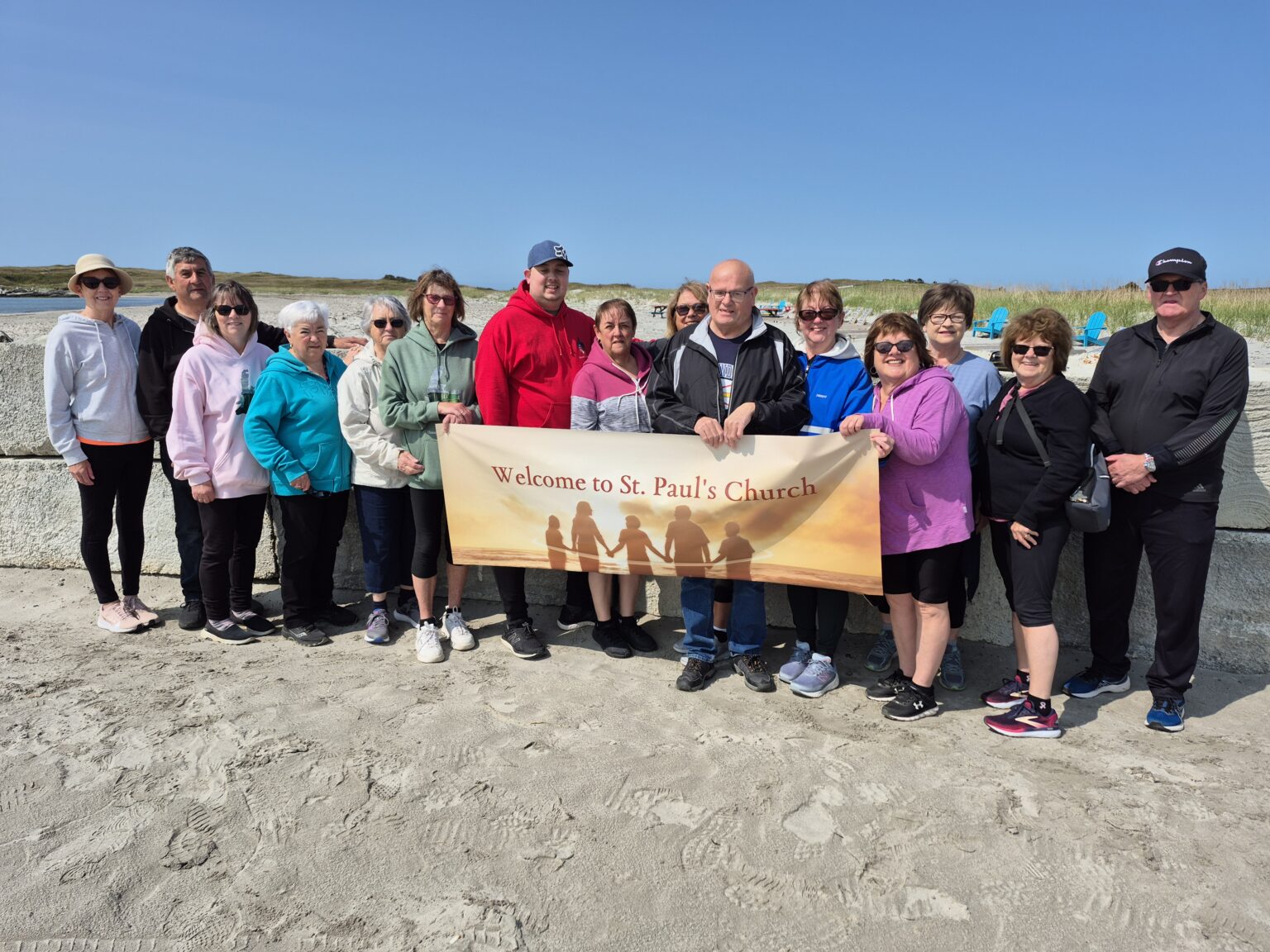 a group of people stand on a snady beach with a banner