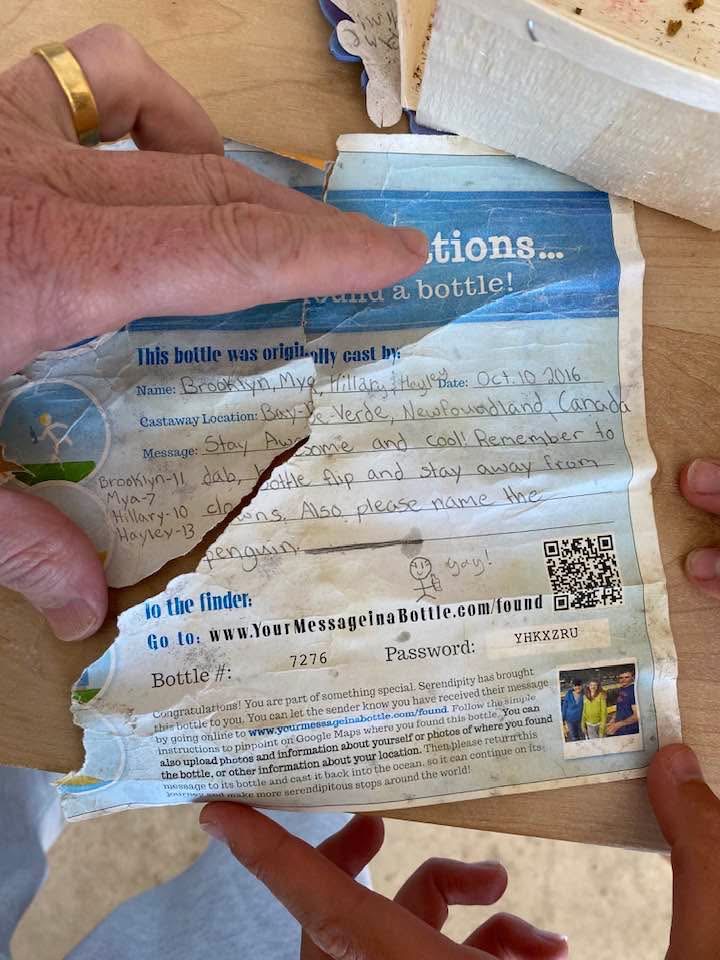 Torn message in a bottle found with handwritten text and a QR code.