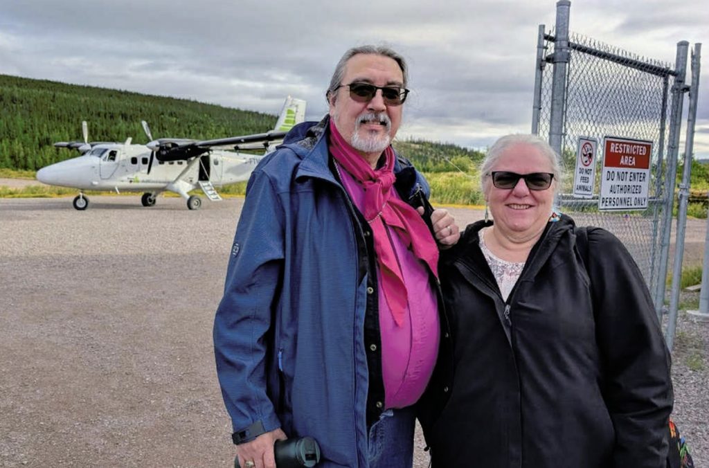 two people stand in front of a twin otter airplane