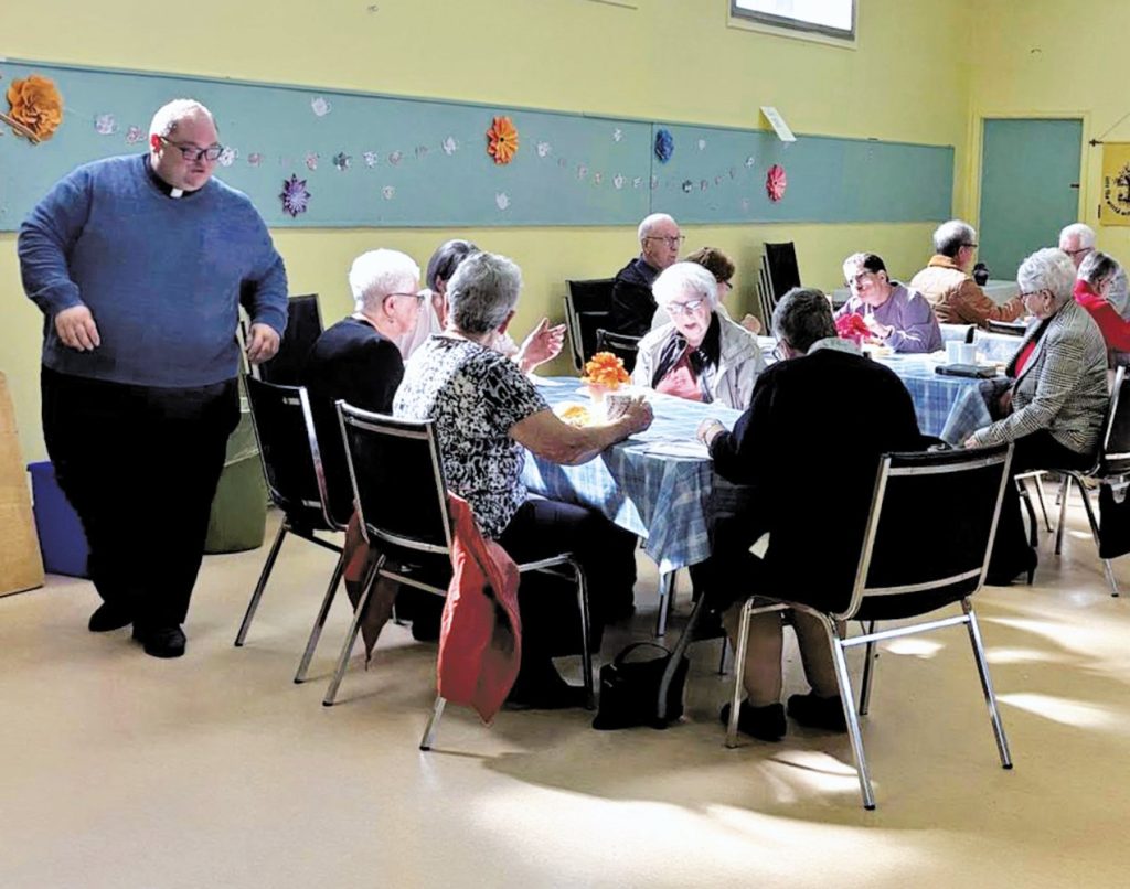 many people sitting around a table in at a church potluck