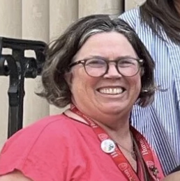woman in pink shirt and glasses smiling at the camera