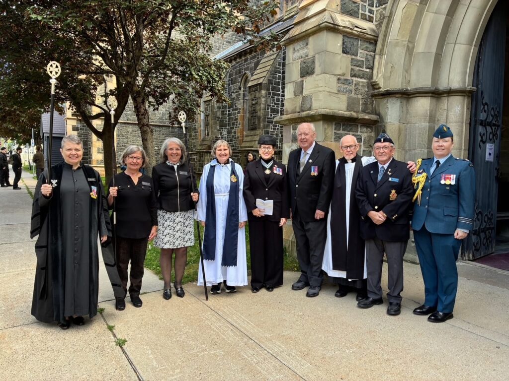 Group of people, some in vestments and military uniform, standing outside a church.
