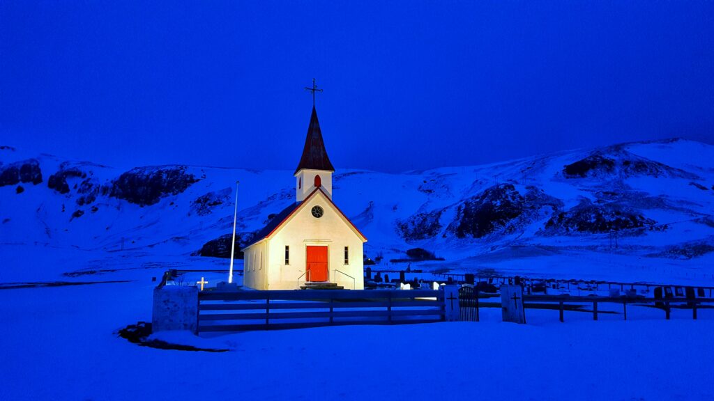 an illuminated white church at night in the snow