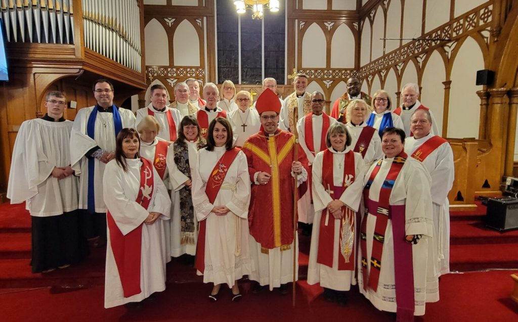 Group of clergy in red vestments inside a church (at an ordination)