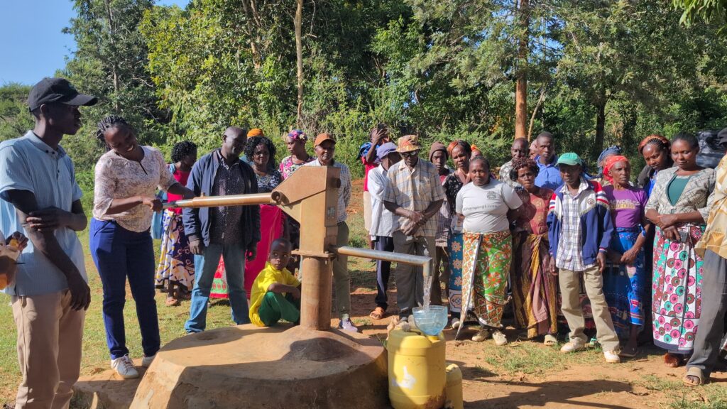 Group of people standing by a water pump outdoors.
