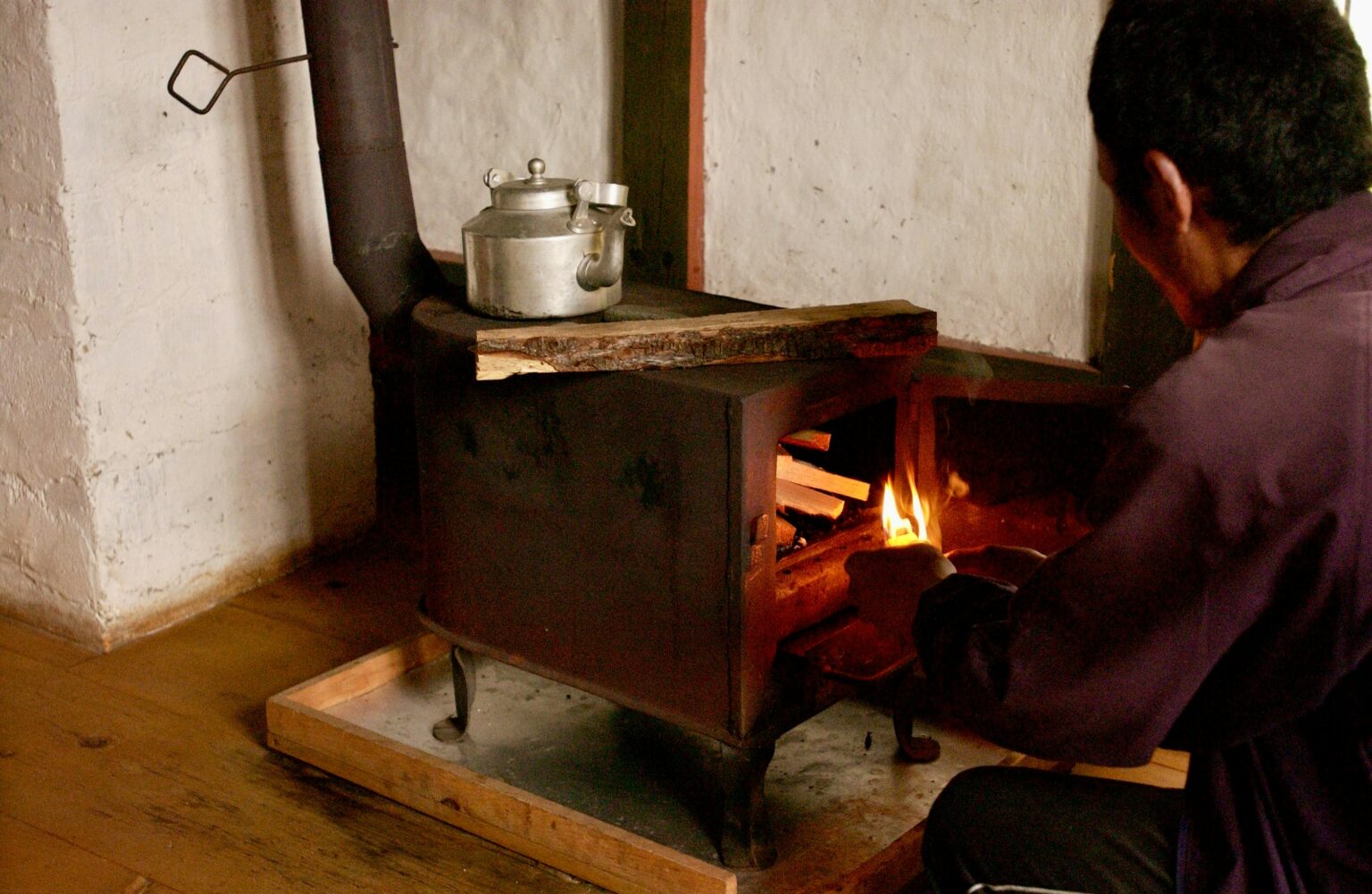 a man putting firewood into a wood burning stove