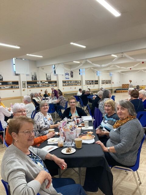 Group of women sitting at tables during an event.