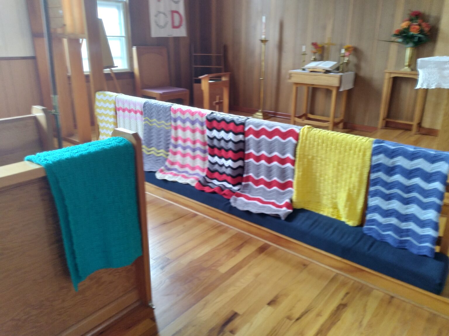 knitted prayer shawls displayed over a communion rail at the front of a church