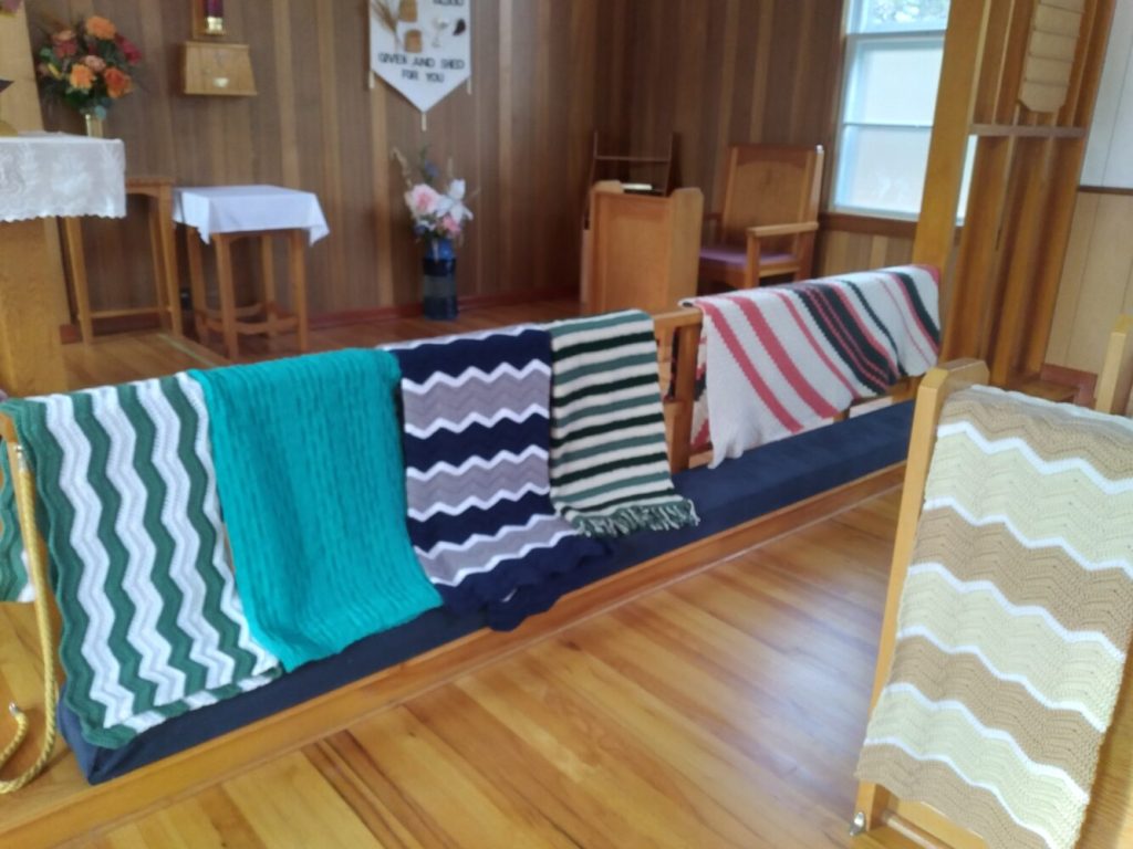 knitted prayer shawls displayed over a communion rail at the front of a church