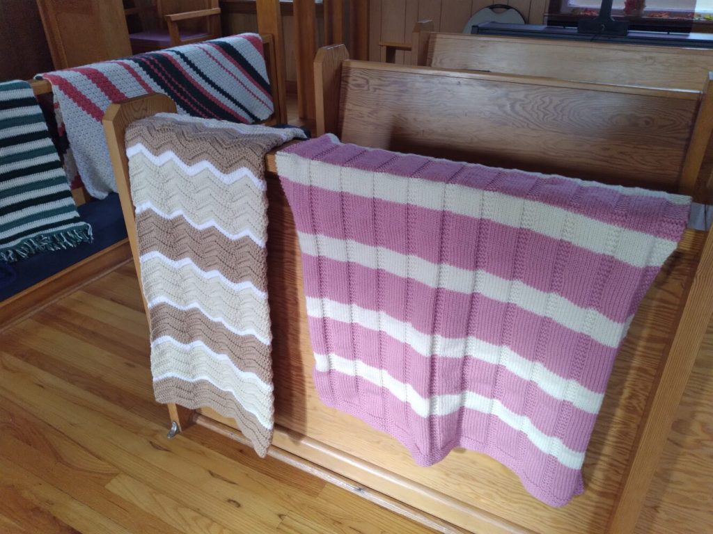 knitted prayer shawls displayed over a church pew