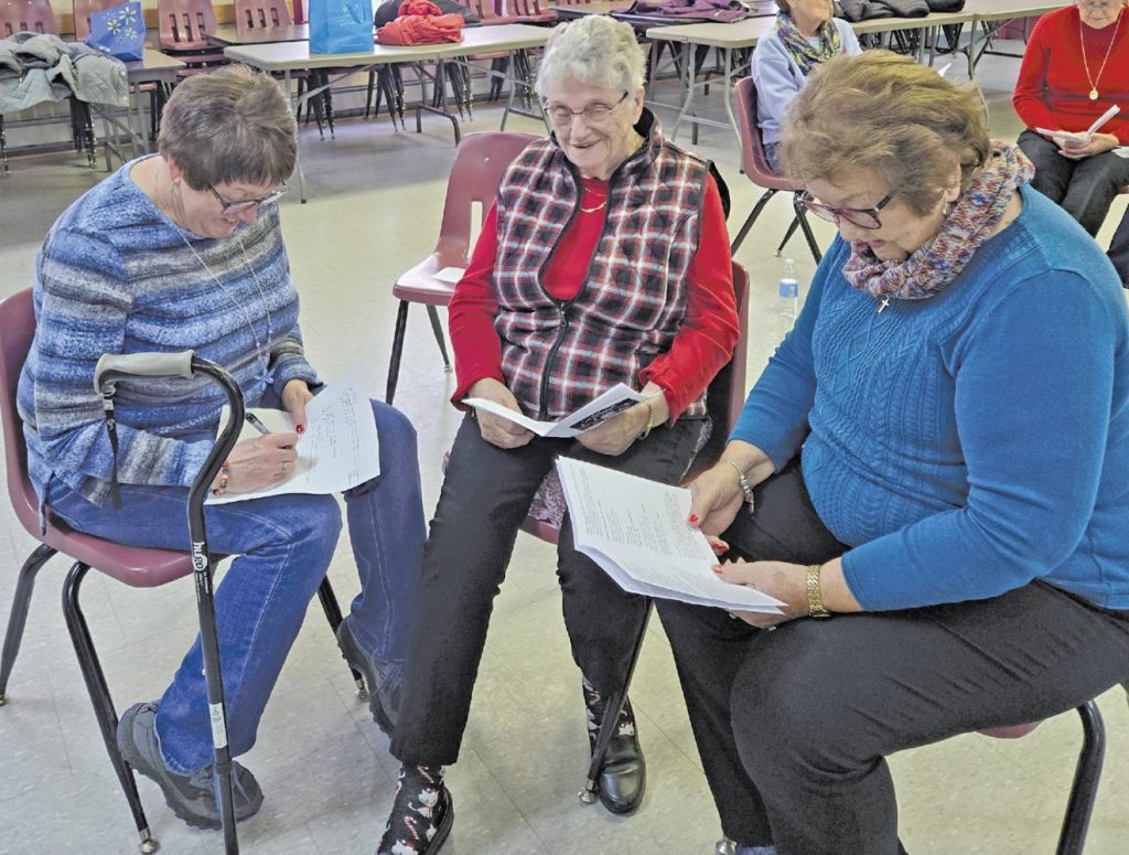 Three women sitting in a circle discussing papers.