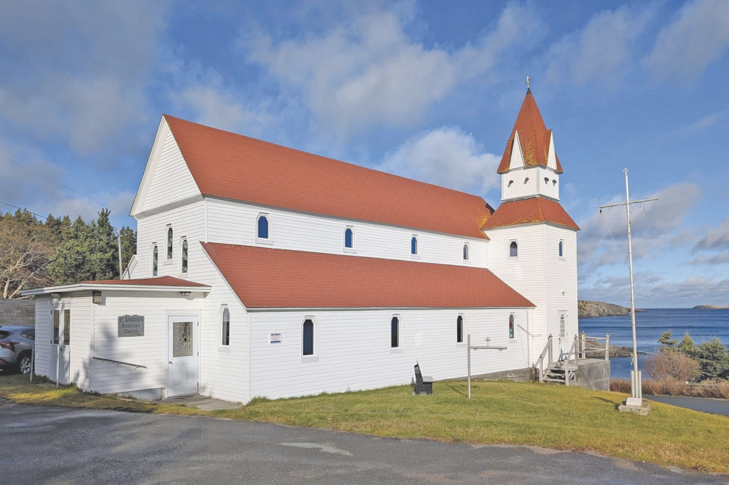 Exterior view of a white church with a red roof situated near a body of water.