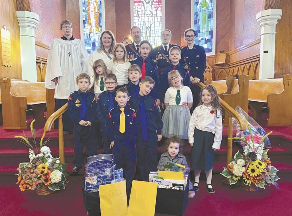 A group of children in uniforms and adults posing for a photo in front of a church altar.