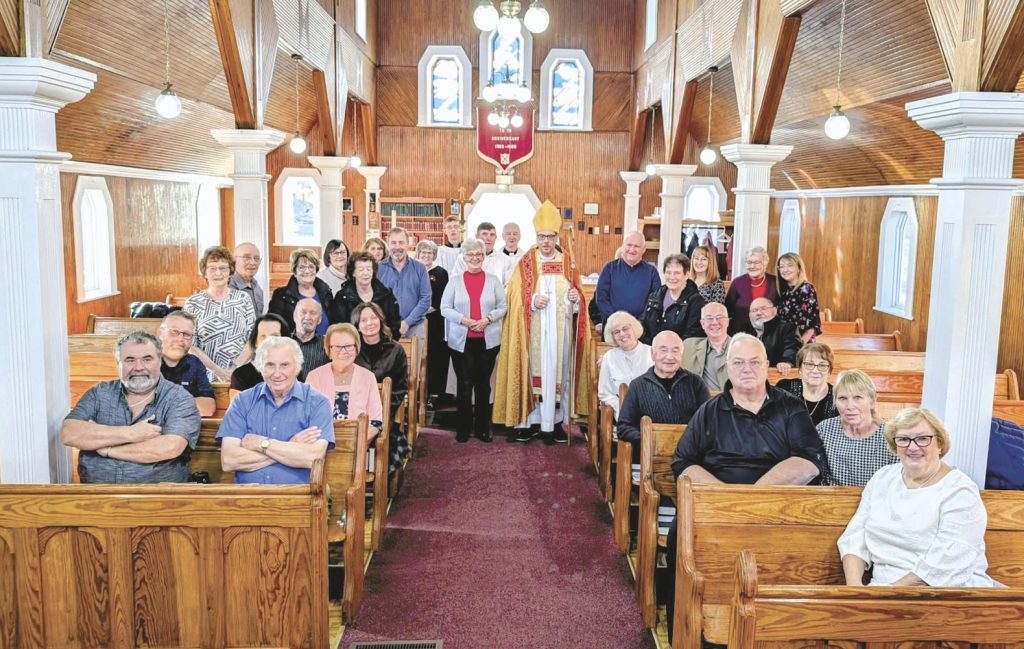 A large congregation posing for a group photo inside the pews of a wooden church.