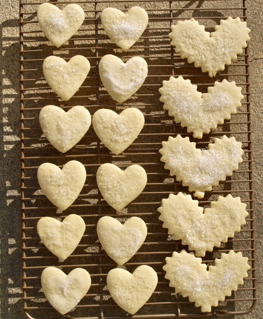 a selection of shortbread cookies in the shape of hearts on a cooling rack