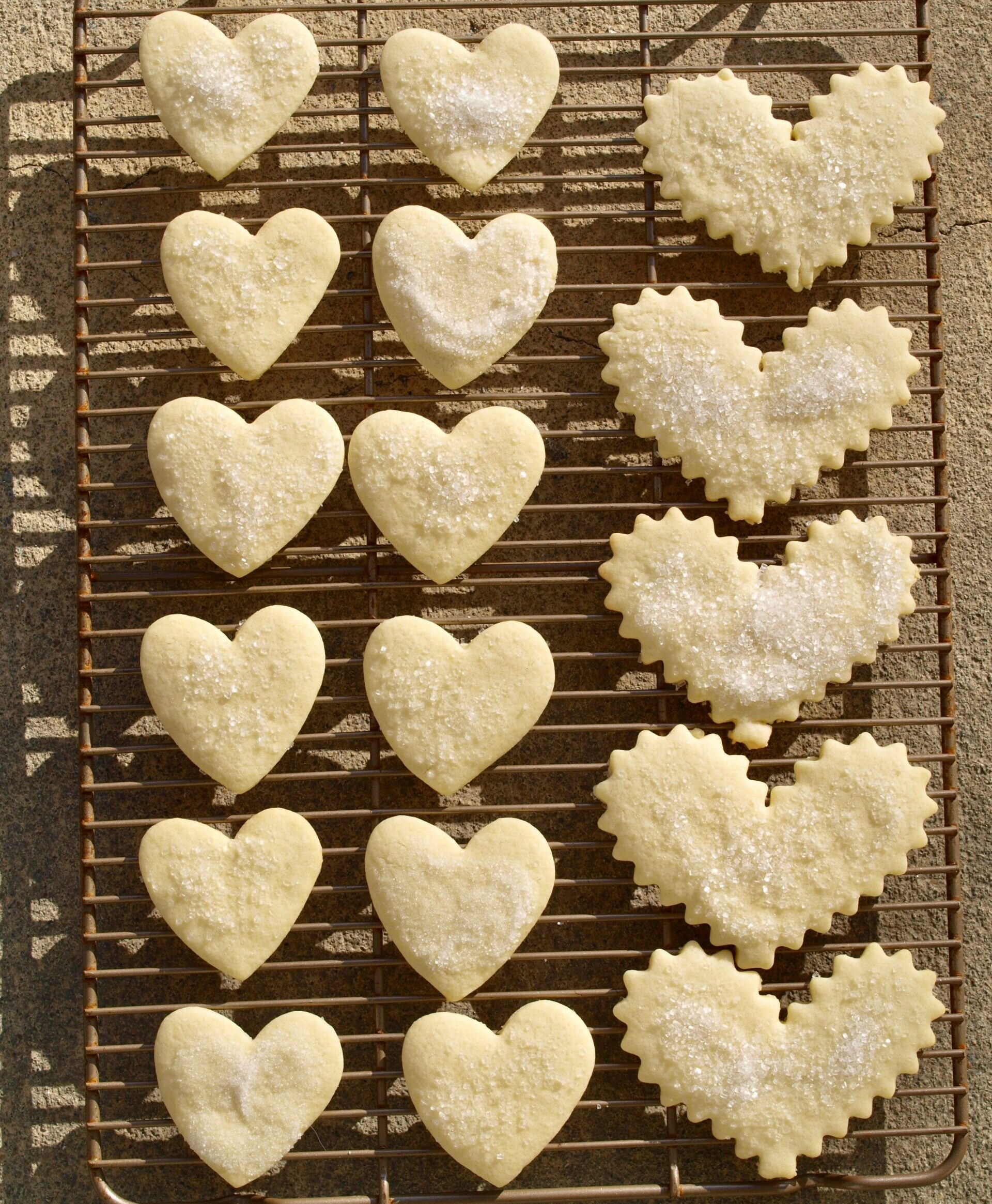 a selection of shortbread cookies in the shape of hearts on a cooling rack