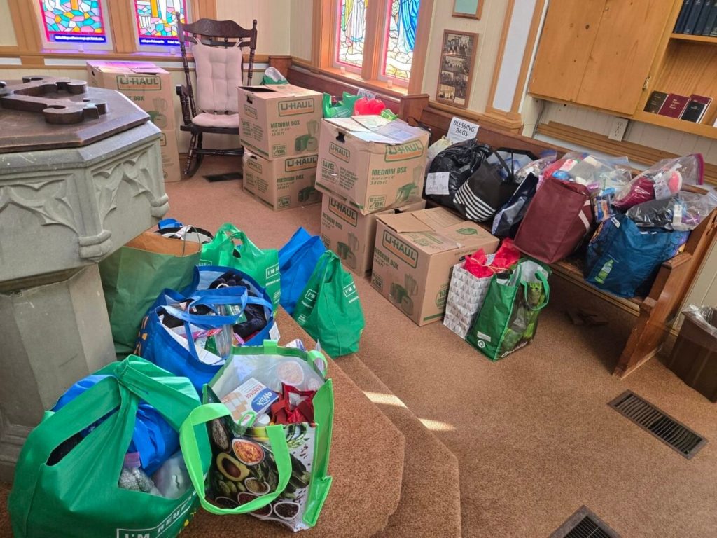 Dozens of reusable shopping bags and U-Haul boxes filled with donations inside a church.