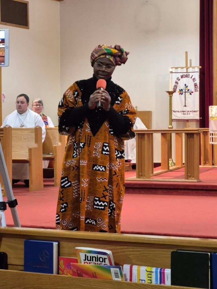 a woman in traditional African clothing singing into a microphone at the front of a church