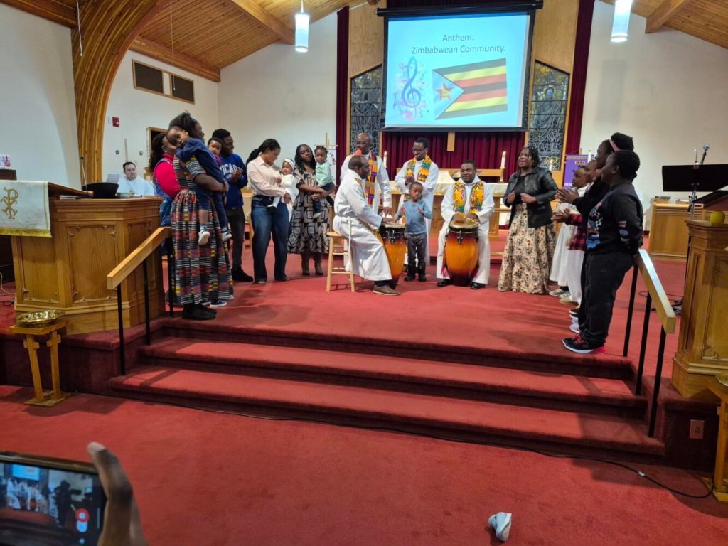 a group of people in the fron tof a church singing and dancing and drumming with traditional African drums