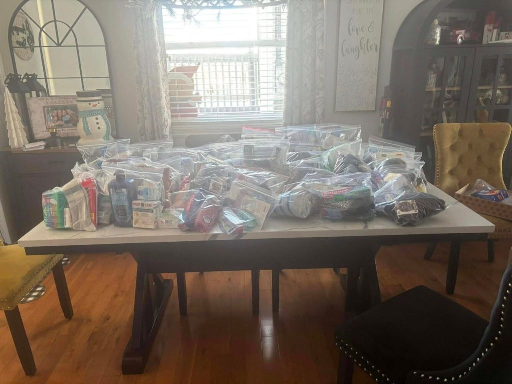 Numerous clear zip-top bags filled with toiletries and hygiene supplies covering a white dining table.
