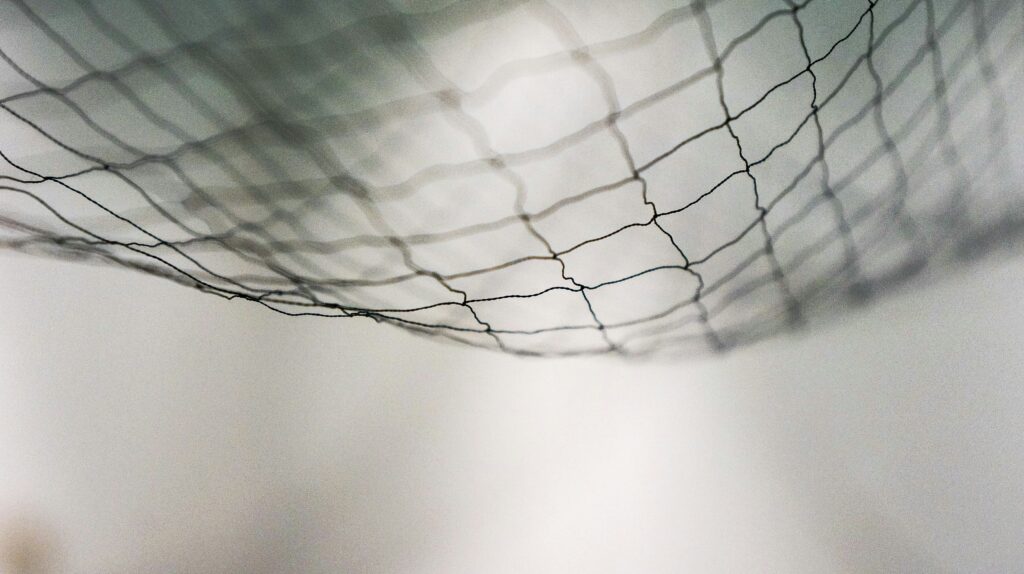 looking up through a net at the sky on a grey day