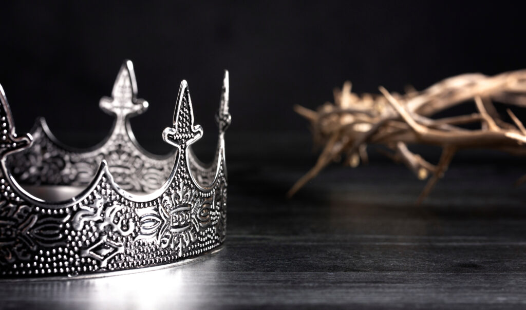 photograph of a silver crown in the foreground and a crown of thorns in the background