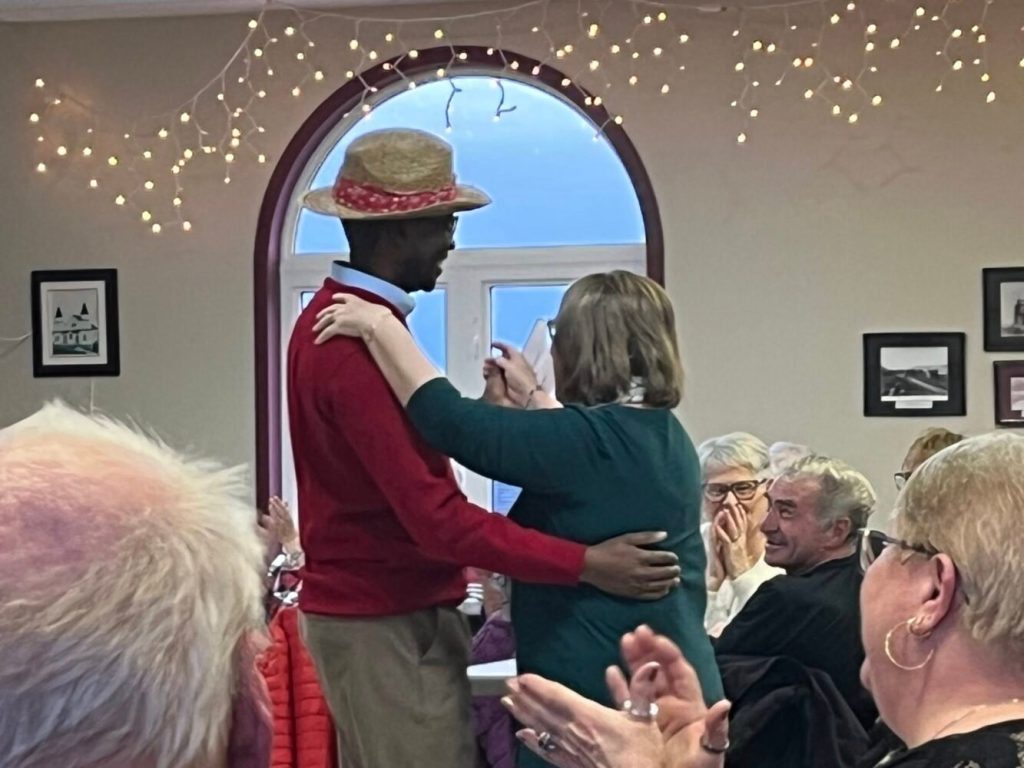 A couple dancing in a decorated hall while an audience watches and applauds.