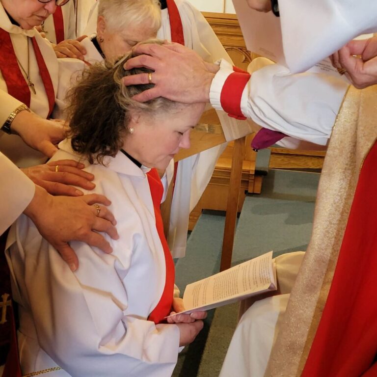 a woman kneels and has hands placed on her head