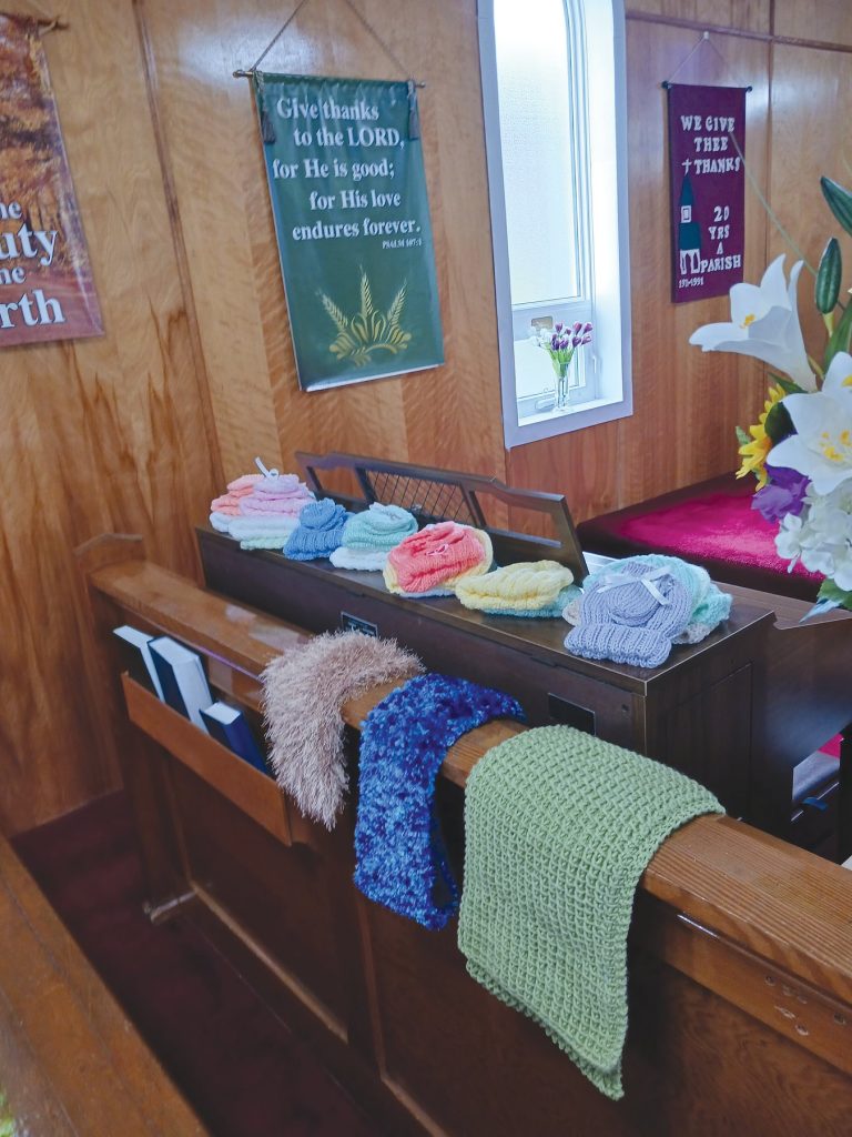 Knitted hats on a wooden organ and scarves draped over a church pew.