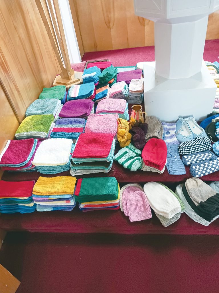 Stacks of colourful knitted washcloths and items arranged on steps.