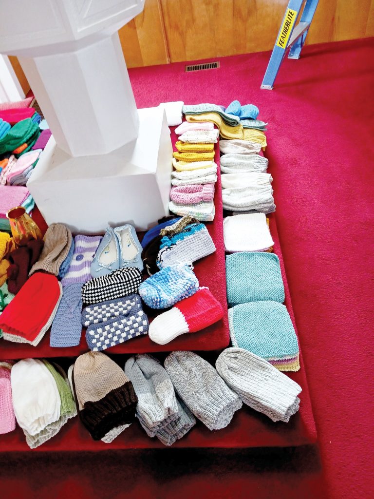 Colourful knitted hats, slippers, and small blankets displayed on carpeted steps.