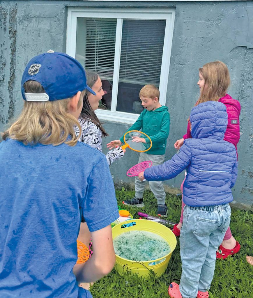 group of young people play ourdoors with bubbles and bubble wands