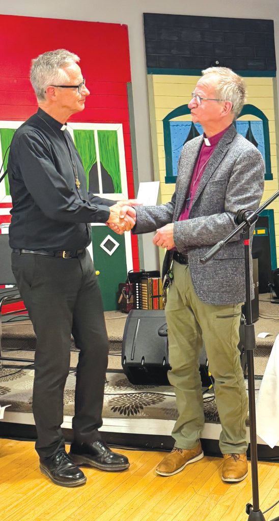 a priest and a bishop, both male, shake hands at the front of a church