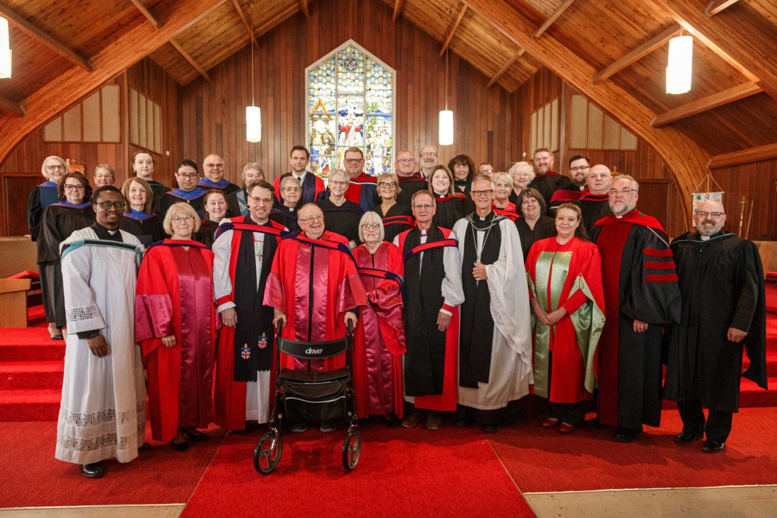 Large group portrait of clergy and graduates in academic and religious robes inside a church.