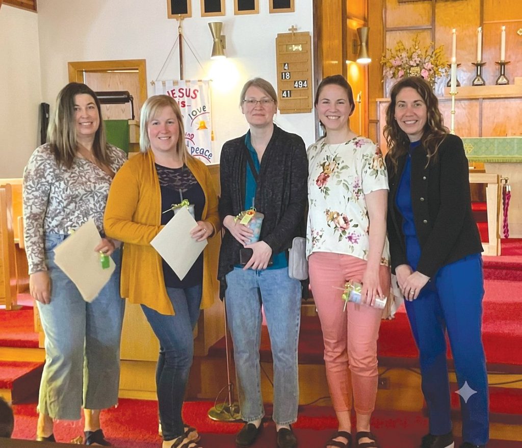 Five smiling women standing together in a church interior.