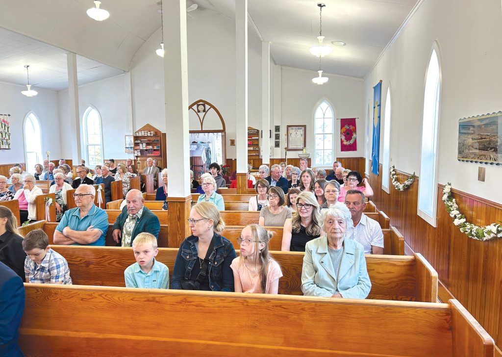 congregatin of a church with wooden pews and white walls