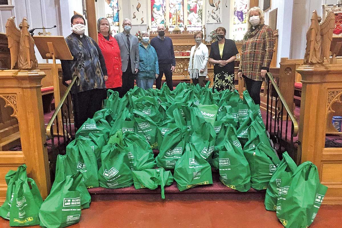 Members of the congregation from St. Thomas’ Church stand in the chancel with the bags of groceries that were collected for the Emmaus House Food Bank